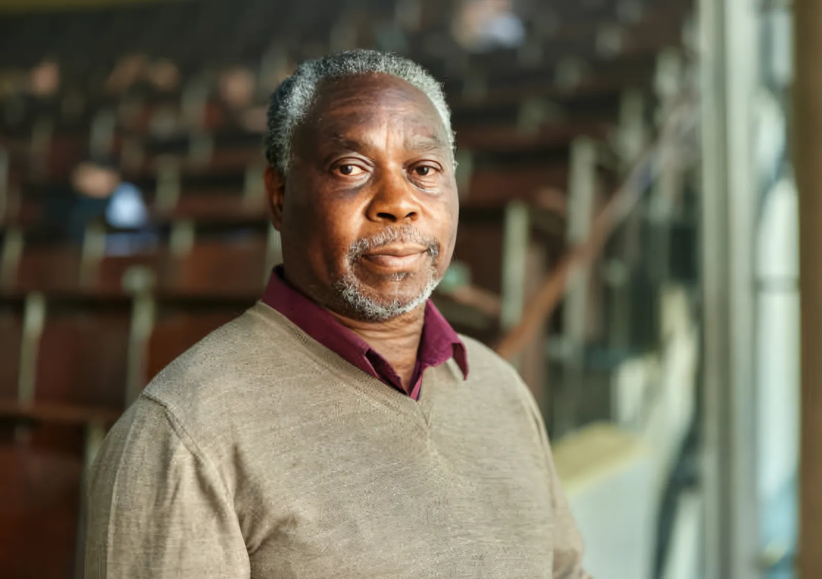 An older man seated in a lecture hall, ready for his interview